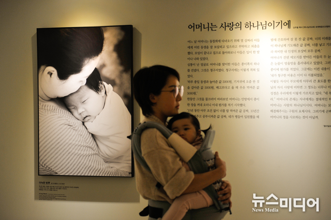 아기를 안고 사진전을 관람중인 관객